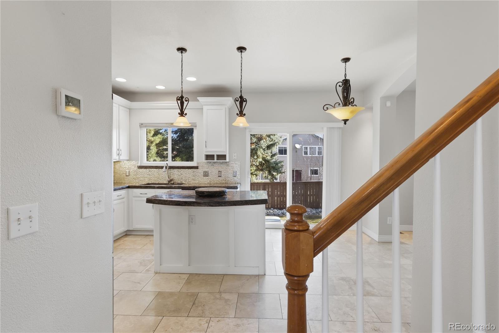 3807 Garnet Way Highlands Ranch, CO 80126 - Photo 7 of 38 a kitchen with kitchen island granite countertop a sink a counter top space and cabinets