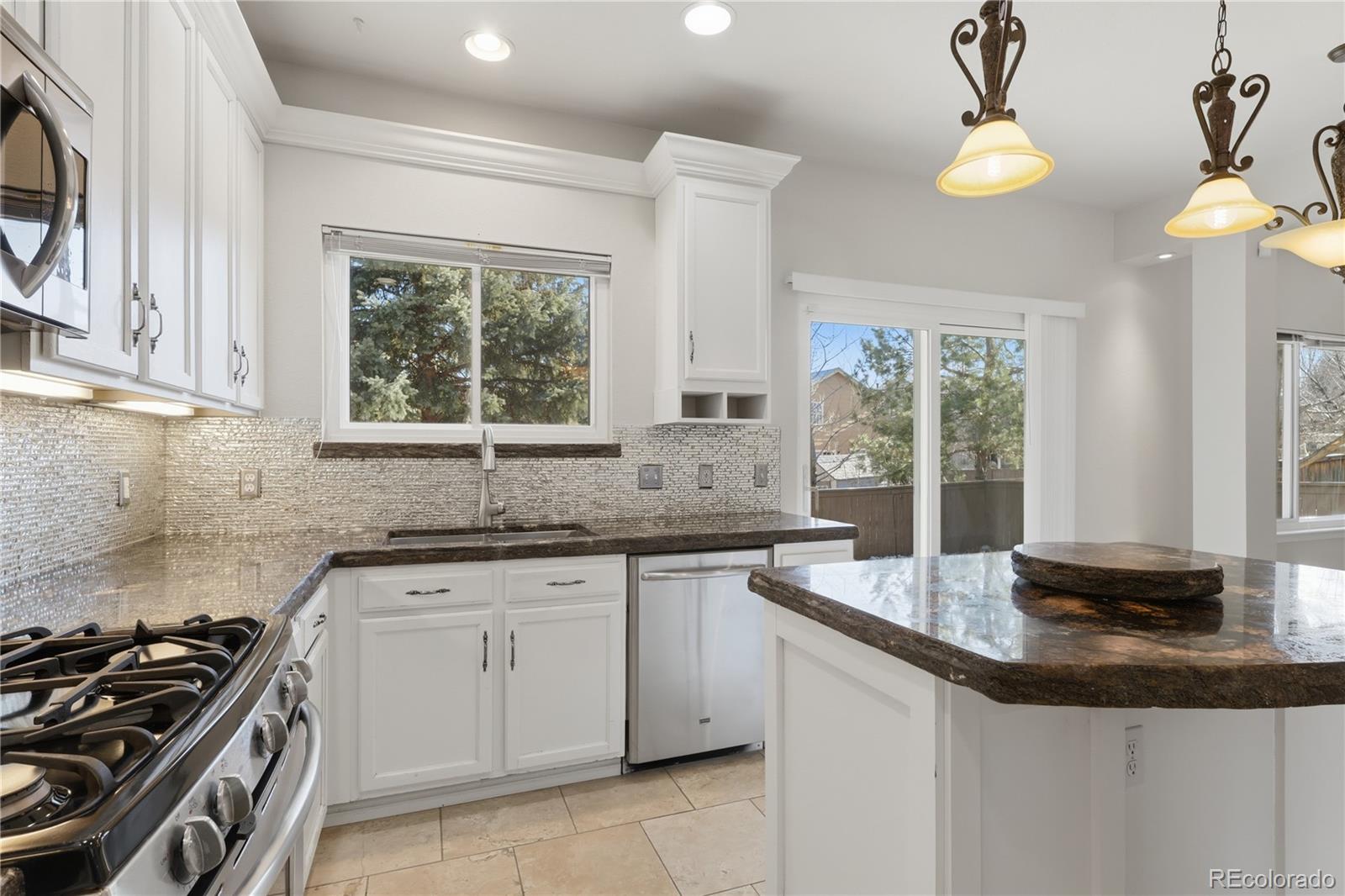 3807 Garnet Way Highlands Ranch, CO 80126 - Photo 8 of 38 a kitchen with granite countertop a sink a stove and a window