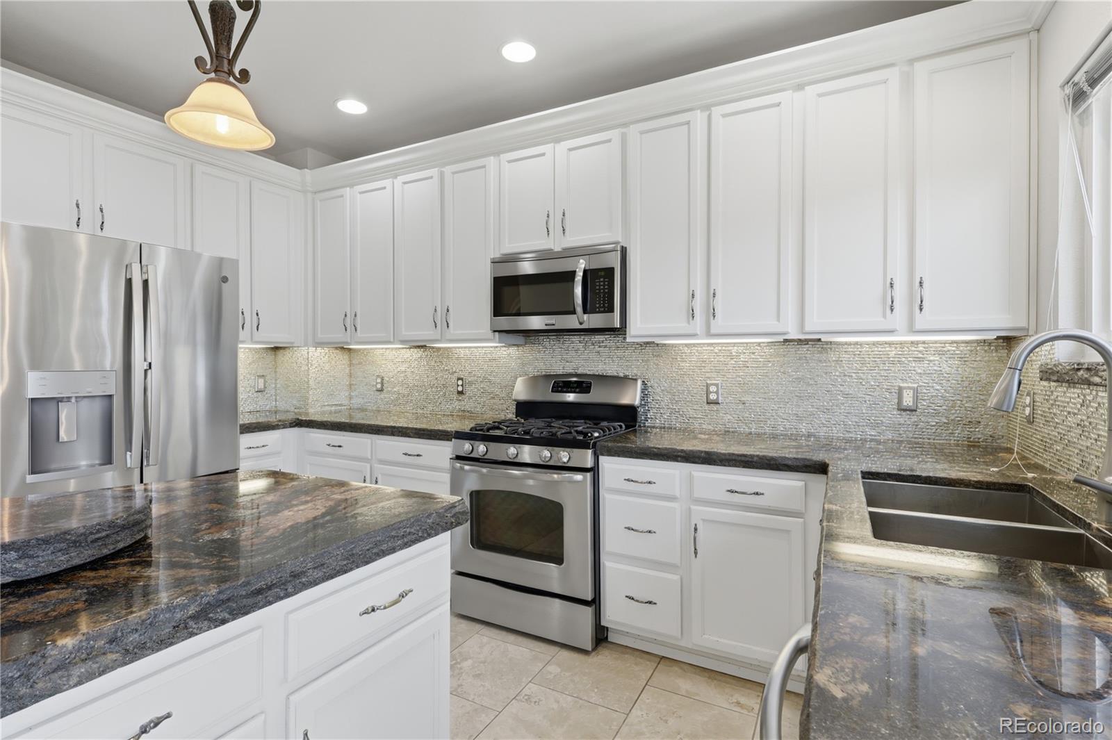 3807 Garnet Way Highlands Ranch, CO 80126 - Photo 9 of 38 a kitchen with granite countertop a stove sink and refrigerator