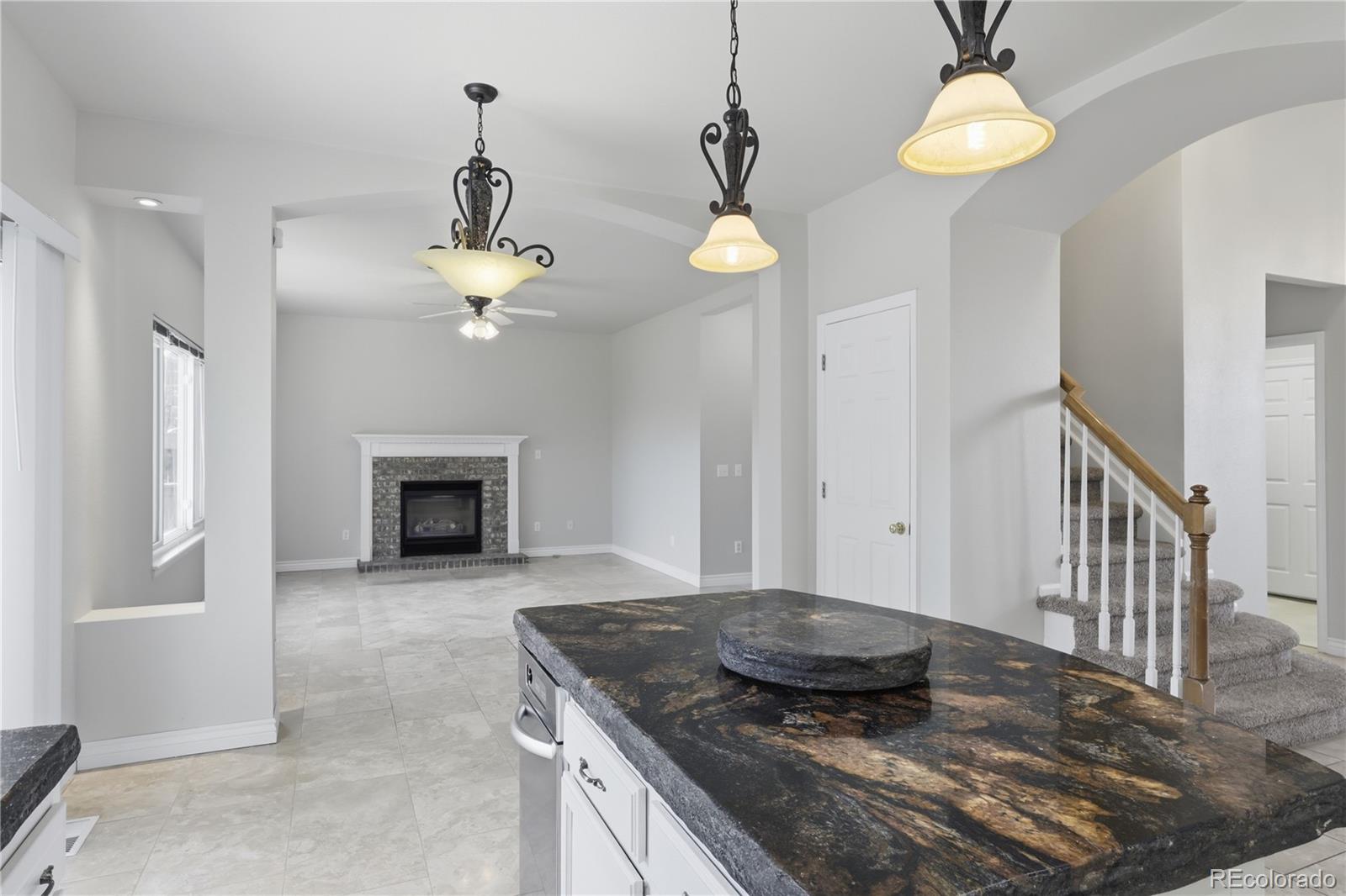 3807 Garnet Way Highlands Ranch, CO 80126 - Photo 10 of 38 a kitchen with kitchen island granite countertop stainless steel appliances a stove a refrigerator and a fireplace