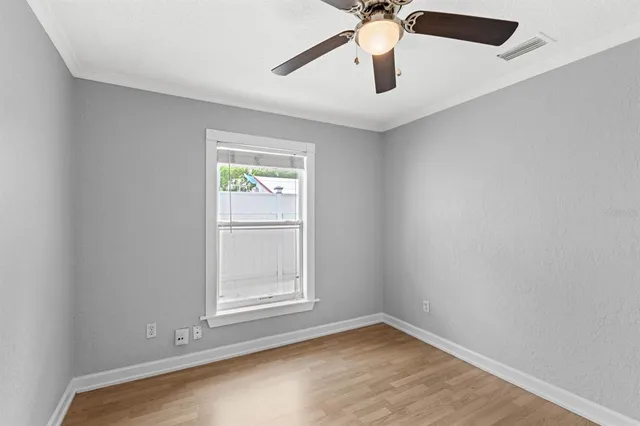 an empty room with windows and fan