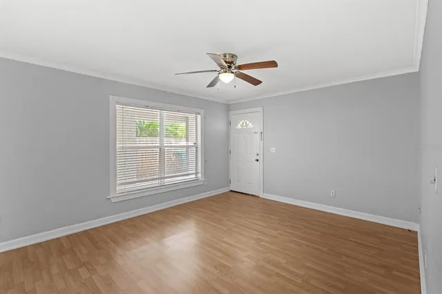 an empty room with wooden floor ceiling fan and windows