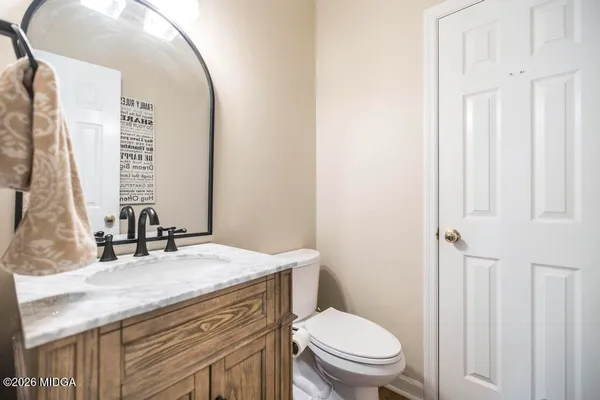 a bathroom with a granite countertop toilet sink and mirror