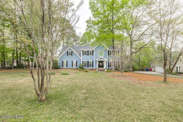 a front view of a house with a yard and large tree