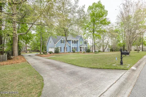 a view of a white house with a big yard and large trees