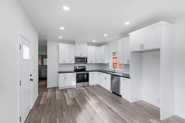 a kitchen with granite countertop a refrigerator and a stove top oven