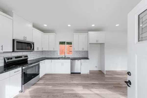 a kitchen with stainless steel appliances granite countertop a sink and white cabinets