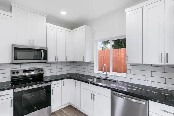 a kitchen with granite countertop white cabinets and black appliances