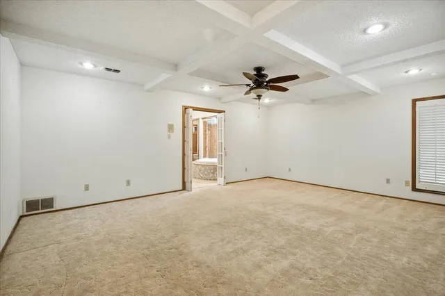 an empty room with chandelier fan and windows