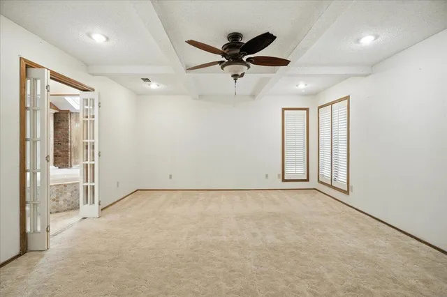 an empty room with ceiling fan and windows