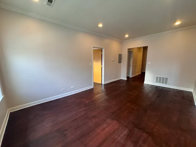 a view of an empty room with wooden floor and closet
