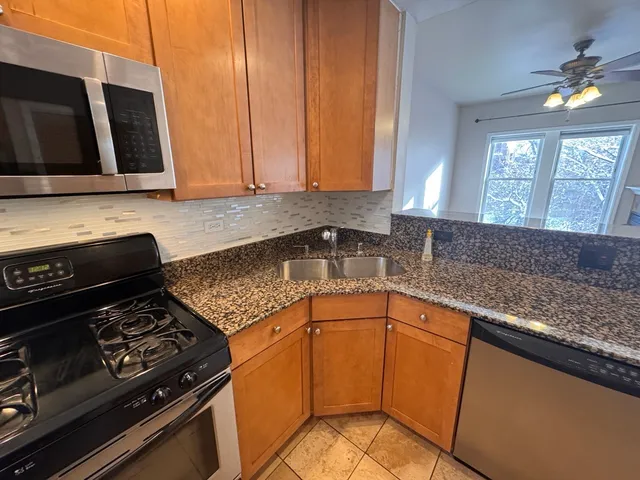 a kitchen with granite countertop a stove sink and cabinets