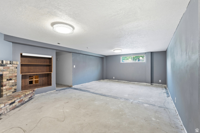 1410 Sumac Drive Logan, UT 84321 - Photo 24 of 28 Spacious room with a brick fireplace and built-in shelving, featuring a window and recessed ceiling lights