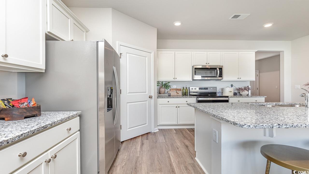 7350 Meadow Walk Loop Loris, SC 29569 - Photo 14 of 26 Kitchen featuring sink, white cabinets, a kitchen breakfast bar, stainless steel appliances, and light wood-type flooring