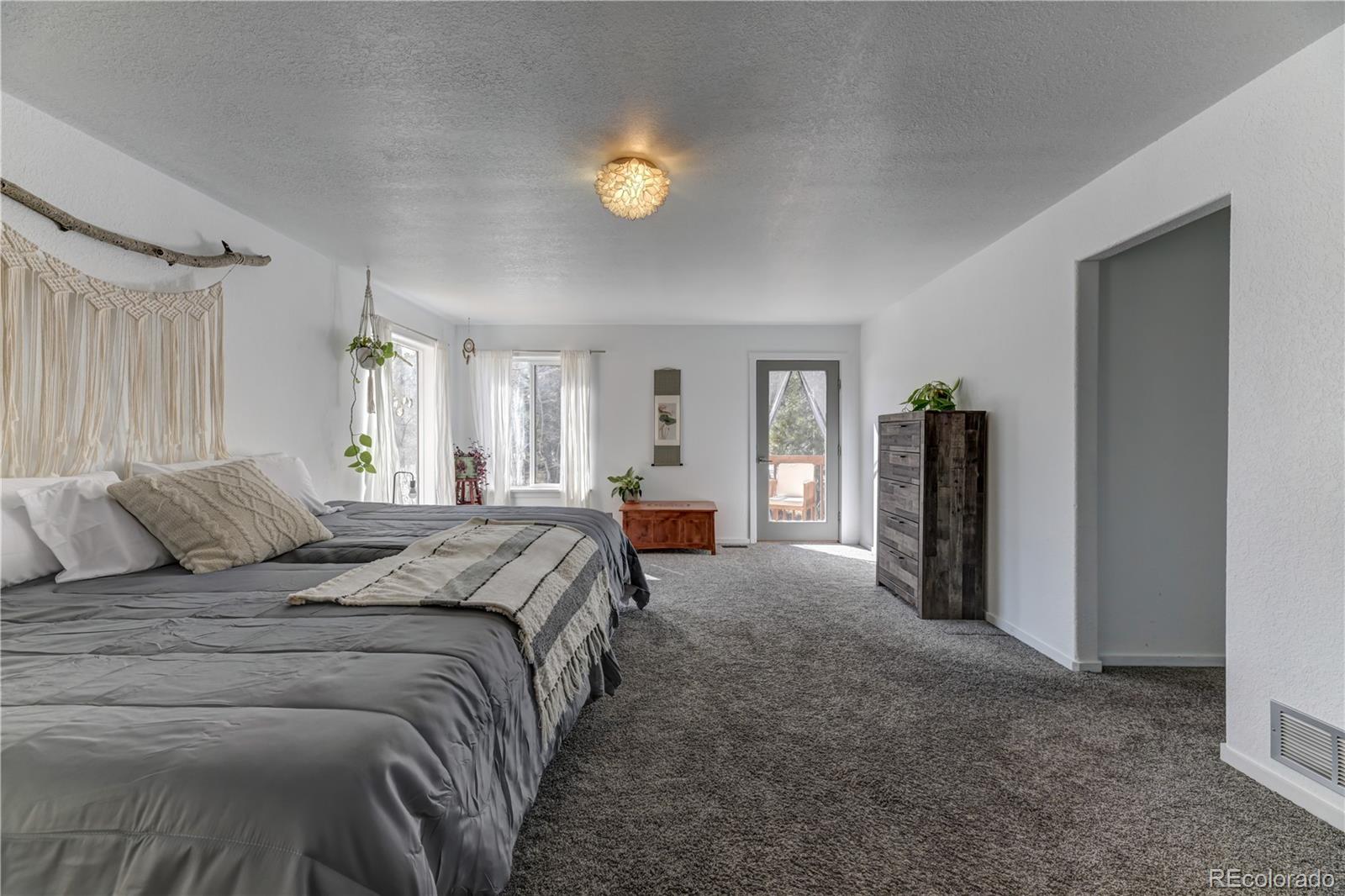 186 Thunder Ridge Road South Nederland, CO 80466 - Photo 31 of 50 a spacious bedroom with a bed and a chandelier