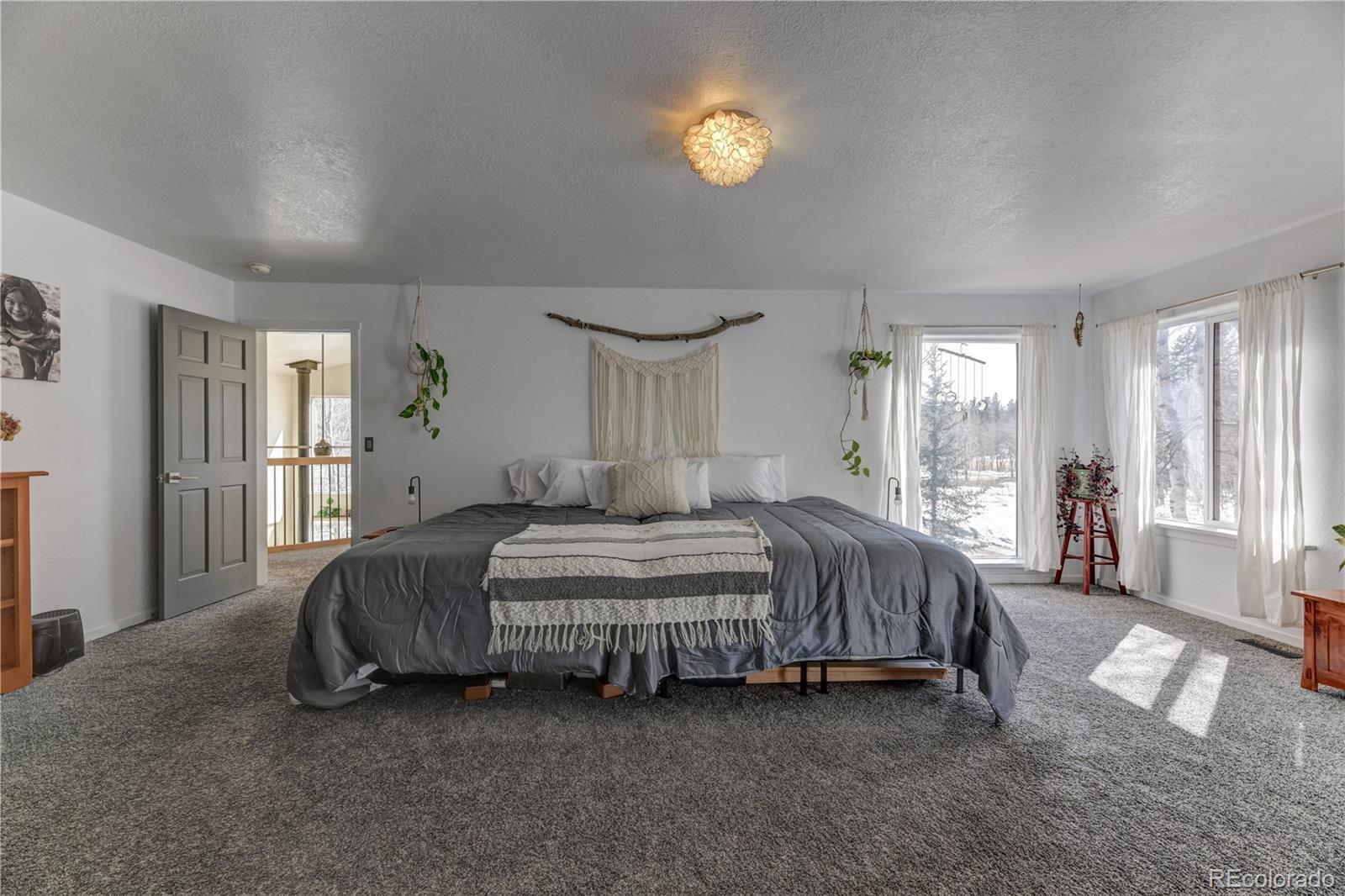 186 Thunder Ridge Road South Nederland, CO 80466 - Photo 32 of 50 a spacious bedroom with a bed and a chandelier