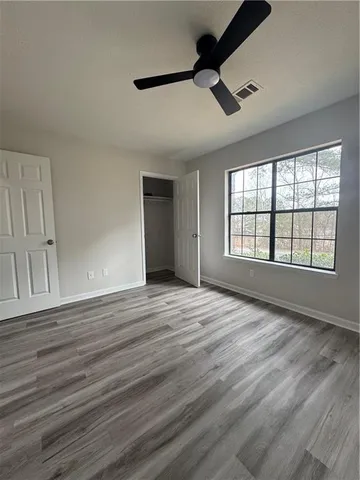 a view of an empty room with a window and wooden floor