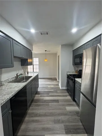 a large kitchen with granite countertop a refrigerator a stove top oven a sink and dishwasher