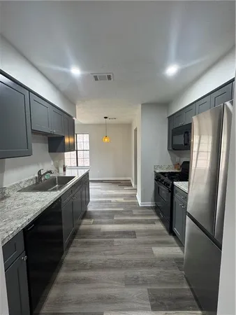 a large kitchen with granite countertop a refrigerator a stove top oven a sink and dishwasher