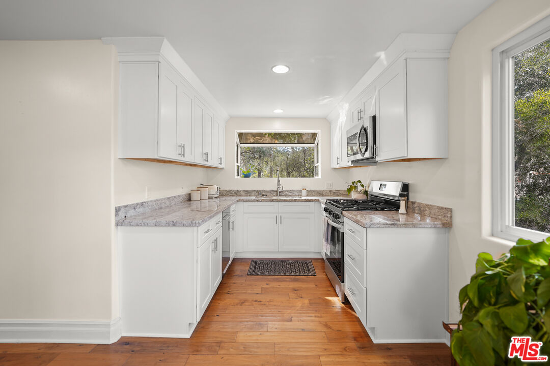21545 Dome Trail Topanga, CA 90290 - Photo 6 of 23 a kitchen with a white stove top oven sink and cabinets
