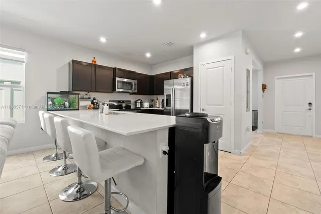 a kitchen with stainless steel appliances a refrigerator a sink a stove a microwave a dining table and chairs