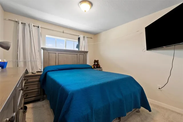 a bedroom with a bed and a flat tv screen on the dresser