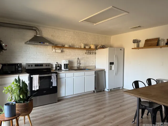 a kitchen with stainless steel appliances granite countertop a stove refrigerator and a dining table with wooden floor