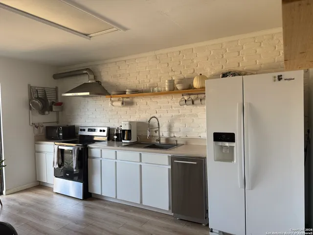 a kitchen with stainless steel appliances a sink a stove a refrigerator and cabinets