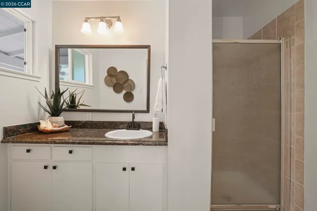 a bathroom with a granite countertop sink a mirror and vanity