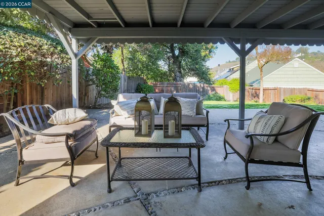 a view of patio with table and chairs and couches with wooden floor and fence
