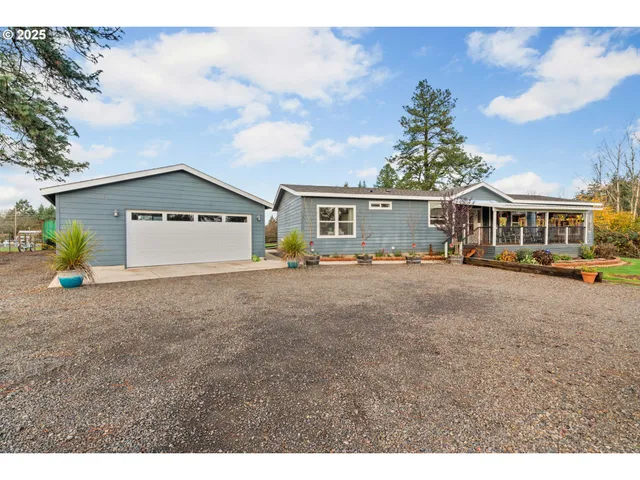 a view of a white house with a big yard and large trees