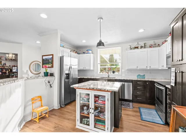 a kitchen with stainless steel appliances kitchen island granite countertop a refrigerator a stove top oven and a sink