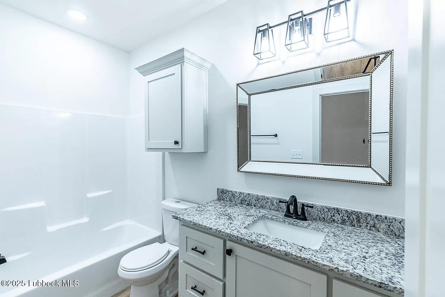 2113 20th Street, Unit A & B Lubbock, TX 79411 - Photo 20 of 31 a bathroom with a granite countertop toilet sink and mirror