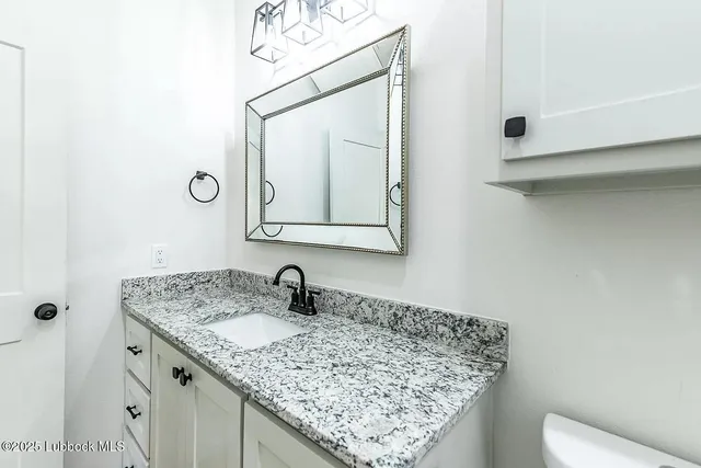 a bathroom with a granite countertop sink a toilet and mirror