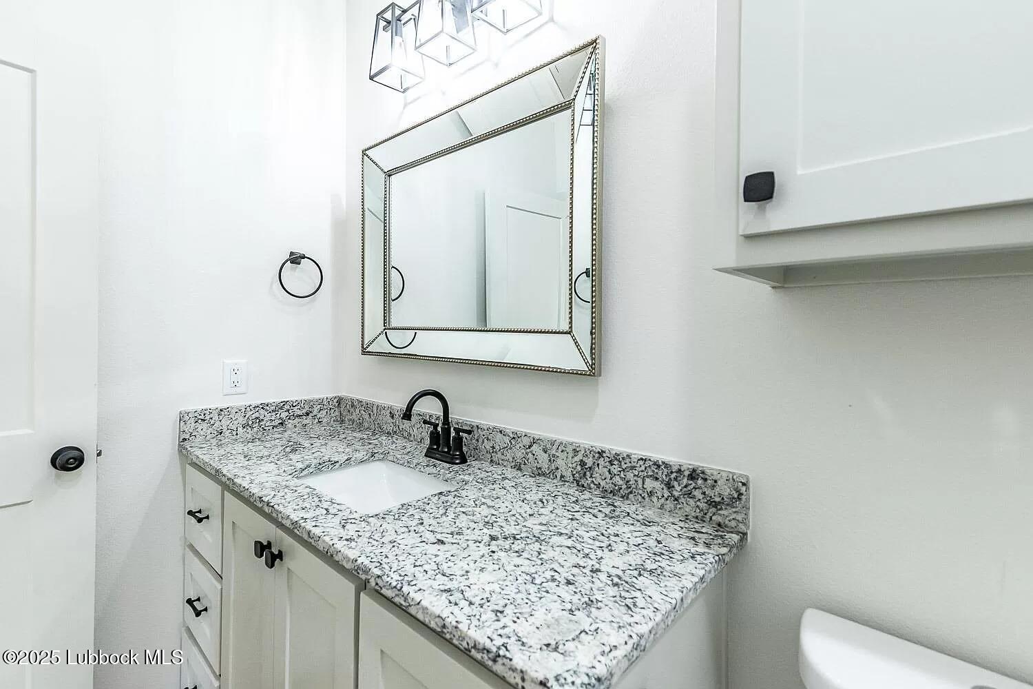 2113 20th Street, Unit A & B Lubbock, TX 79411 - Photo 23 of 31 a bathroom with a granite countertop sink a toilet and mirror