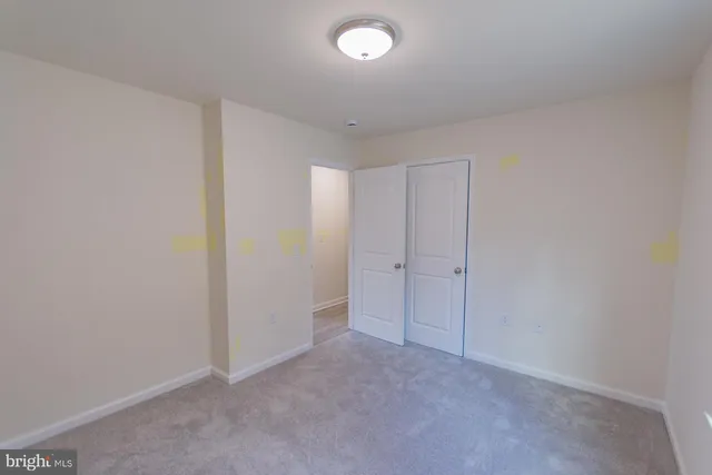 an empty room with chandelier fan and windows