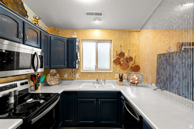 1225 North Dixie Downs Road, Unit 161 St. George, UT 84770 - Photo 9 of 21 Kitchen featuring dark blue cabinetry, white countertops, stainless steel microwave, and white double-basin sink with a window above
