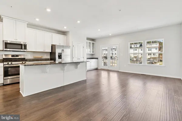 a large kitchen with stainless steel appliances granite countertop a large counter top a sink and a stove with wooden floor