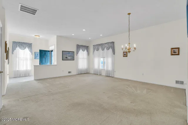 a view of an empty room and kitchen with windows