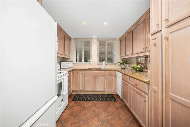 a kitchen with granite countertop white cabinets and white appliances