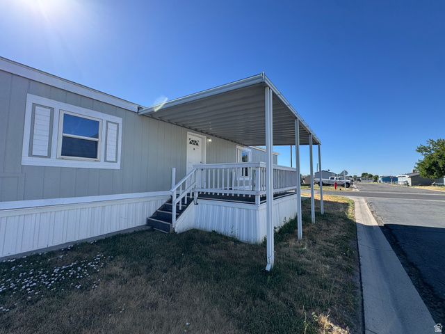 2491 Highway 89, Unit 315 Pleasant View, UT 84404 - Photo 3 of 34 Light gray exterior siding with white trim, white front door, covered porch, white porch railing, and white window shutters