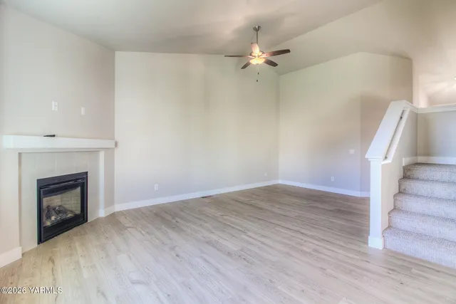 a view of an empty room with wooden floor and fireplace