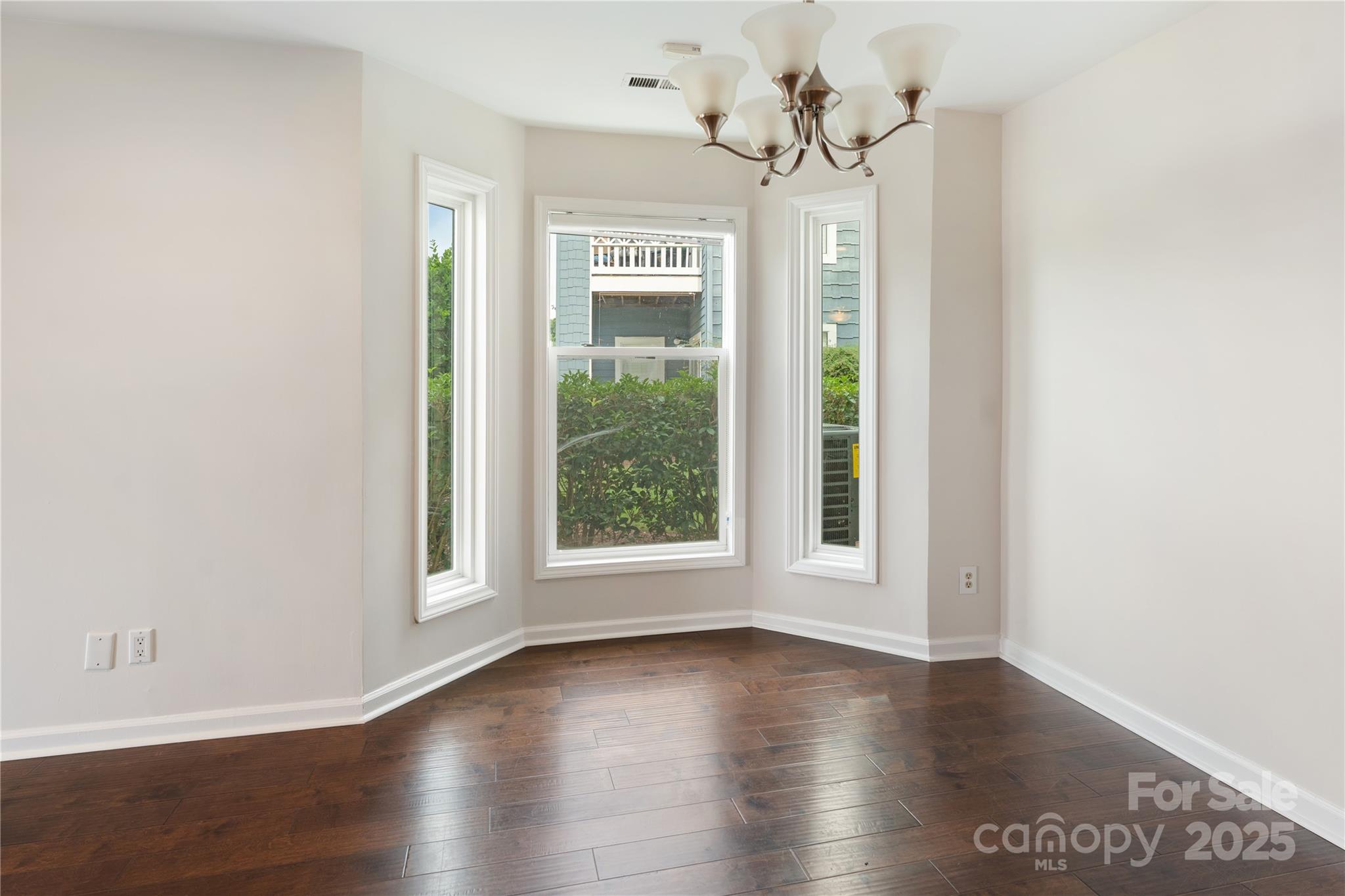 18647 Vineyard Point Lane Cornelius, NC 28031 - Photo 20 of 36 an empty room with wooden floor chandelier and windows