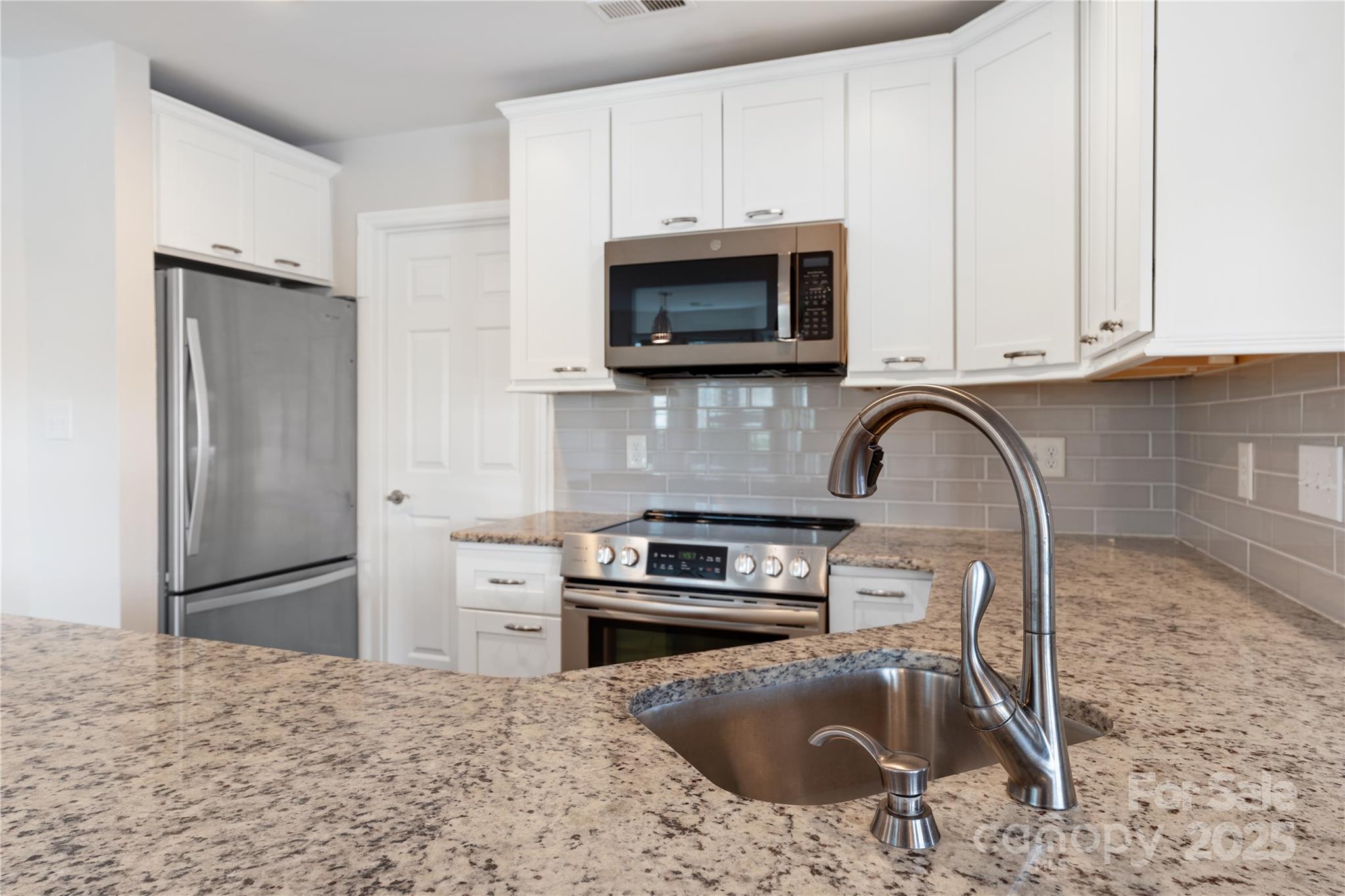 18647 Vineyard Point Lane Cornelius, NC 28031 - Photo 22 of 36 a kitchen with granite countertop a stove a sink and a microwave