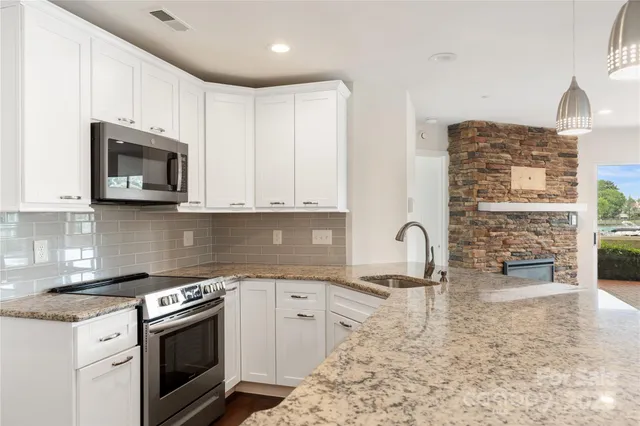 a kitchen with granite countertop a stove top oven microwave and cabinets