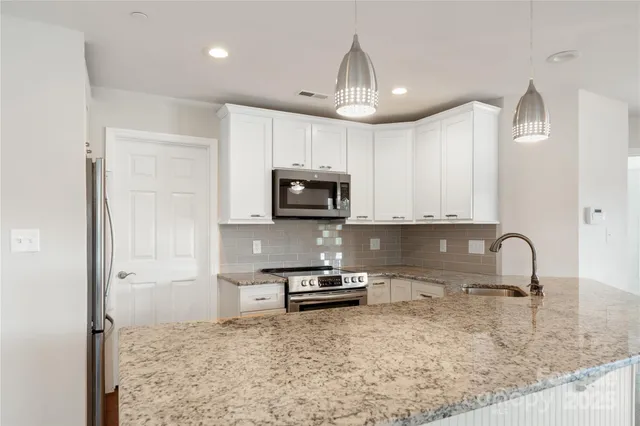a kitchen with granite countertop white cabinets and stainless steel appliances