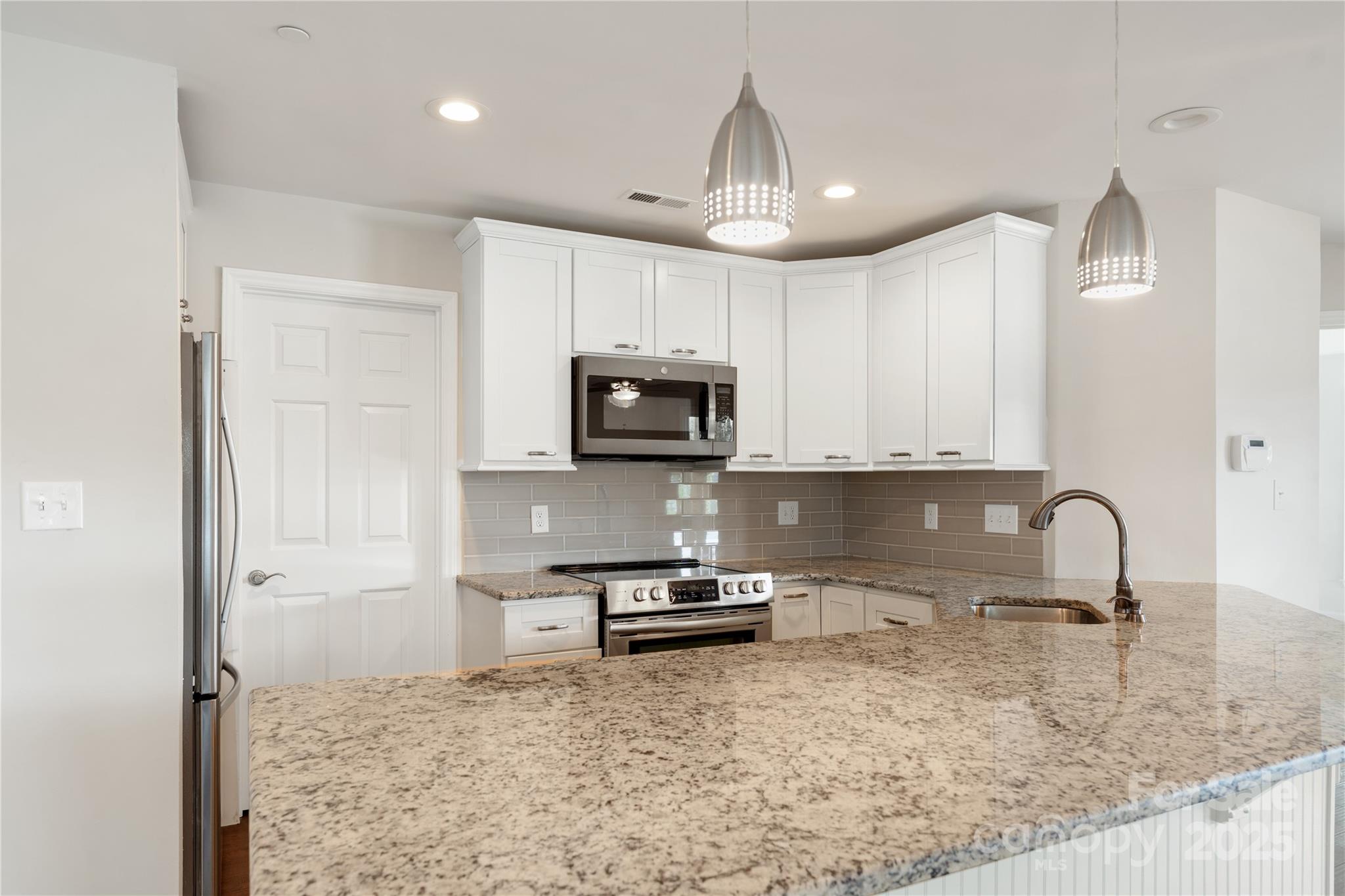 18647 Vineyard Point Lane Cornelius, NC 28031 - Photo 25 of 36 a kitchen with granite countertop white cabinets and stainless steel appliances