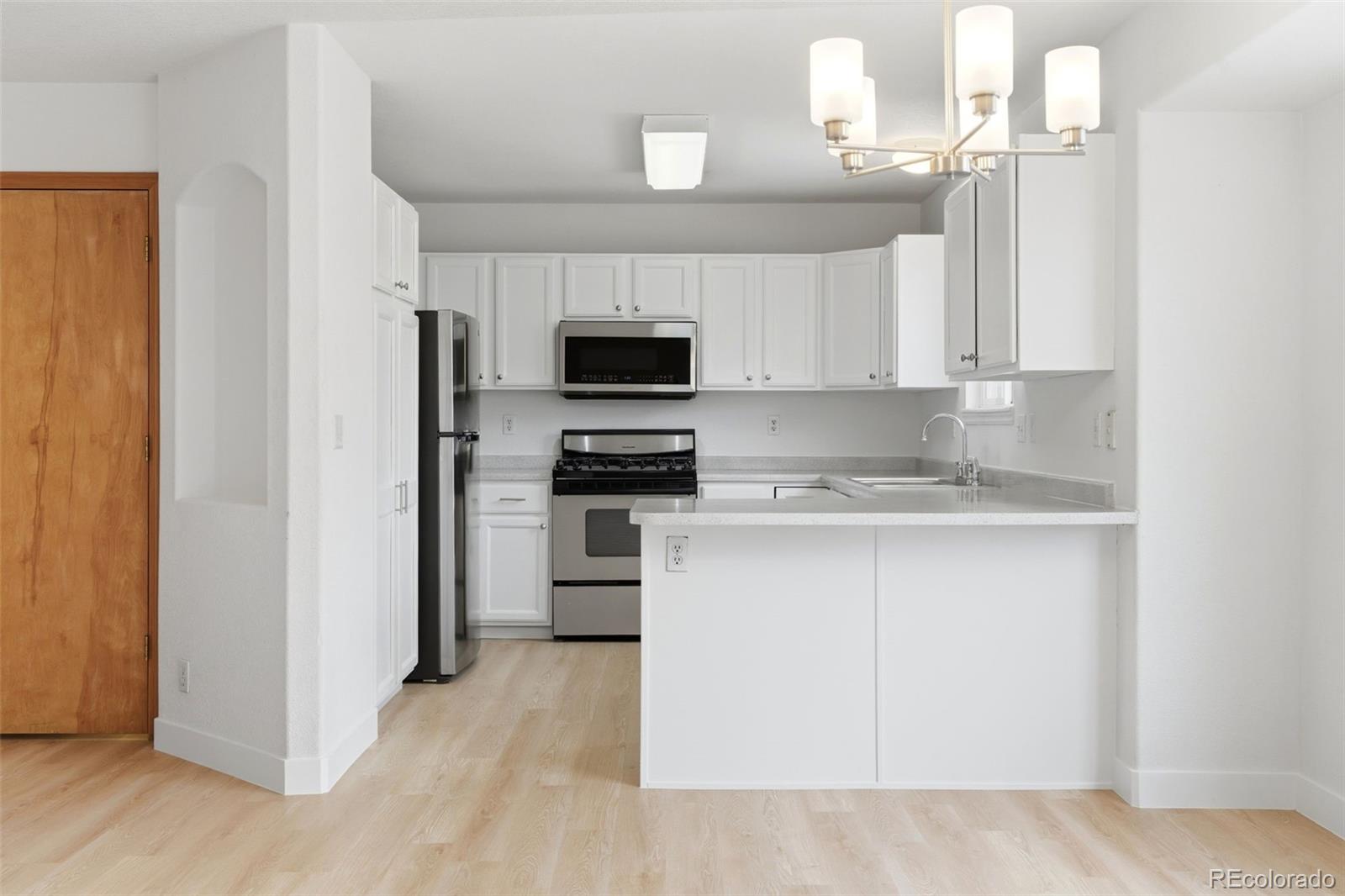 10505 Madison Way Northglenn, CO 80233 - Photo 12 of 49 a kitchen with a refrigerator stove and white cabinets