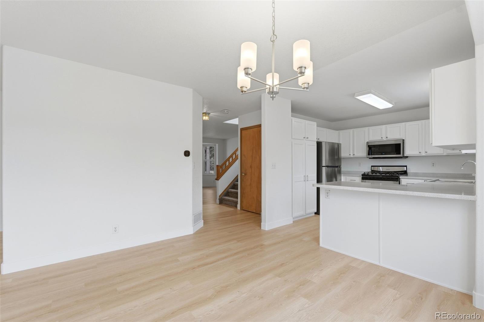 10505 Madison Way Northglenn, CO 80233 - Photo 19 of 49 a view of a kitchen with stainless steel appliances a refrigerator and a wooden floor