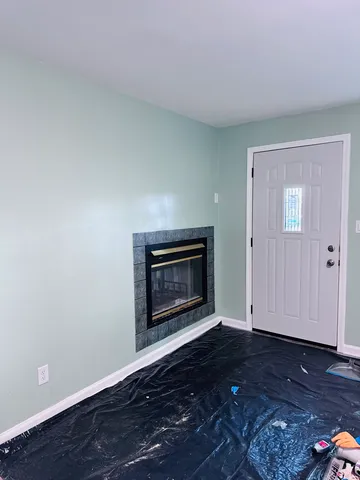 a view of an empty room with wooden floor fireplace and a window